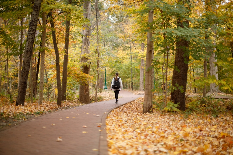 A woman walking through Dunn's Woods in the fall