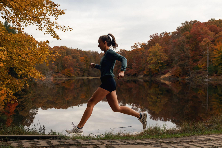 Olivia Ballew running past a lake in the fall