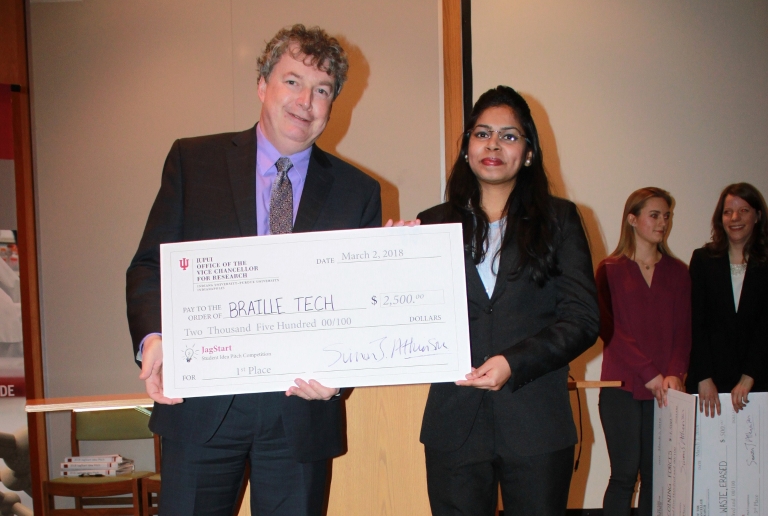 Madhura Mhatre holds her giant check with IUPUI VC for Research Simon Atkinson