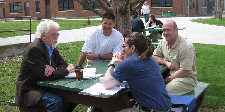Occupational therapy associate professor sits at picnic table with former prison inmates.