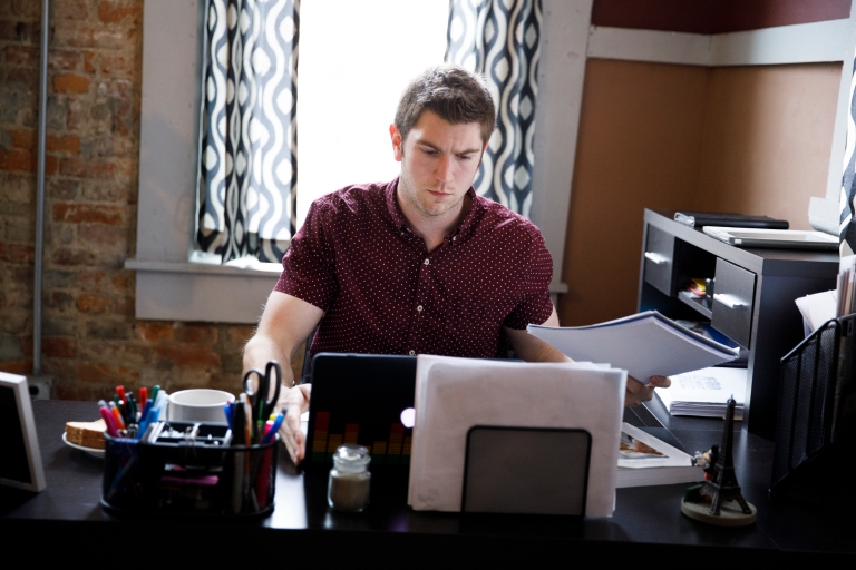 Student sits at his desk looking at a computer.