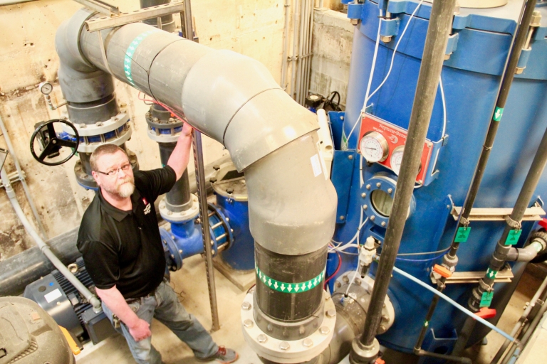 Keith Dollard stands next to a pool filtration system.