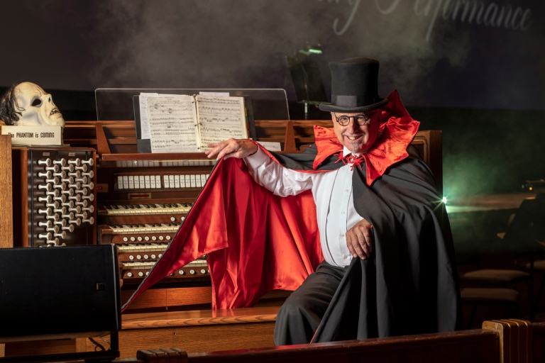 Dennis James wears a costume while posing in front of a pipe organ.