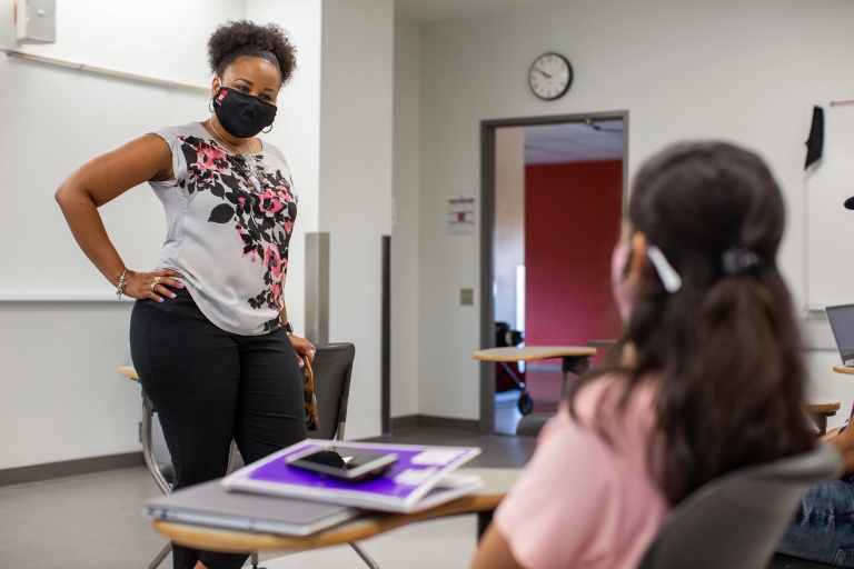 an instructor wearing a mask stands at the front of the class teaching
