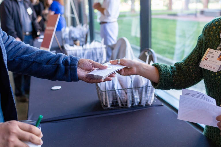 A closeup of two hands exchanging a naloxone kit during a training session