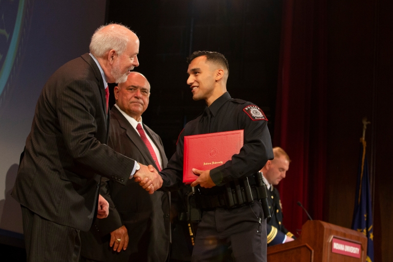 John Applegate shaking hands with an IUPD graduate.