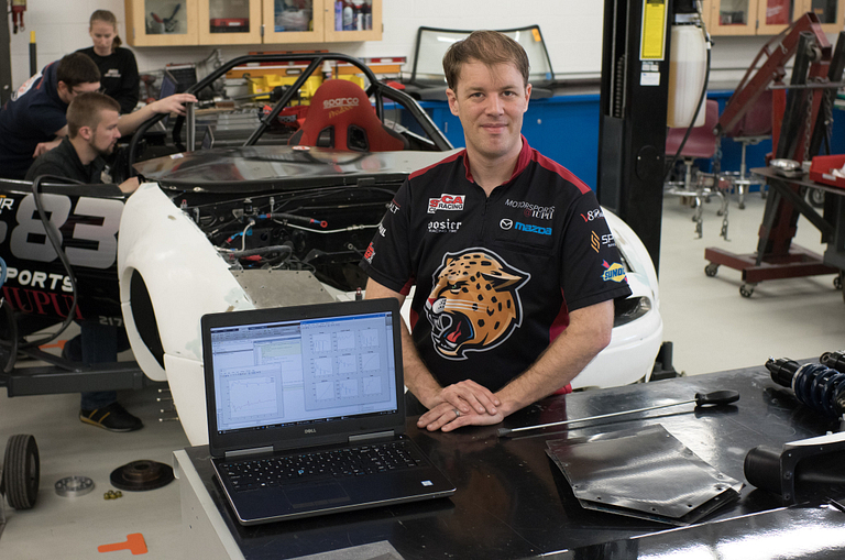 Tyler Stover poses in a motorsports engineering garage.