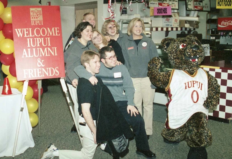 Jinx the jaguar mascot poses for a picture with a collection of students