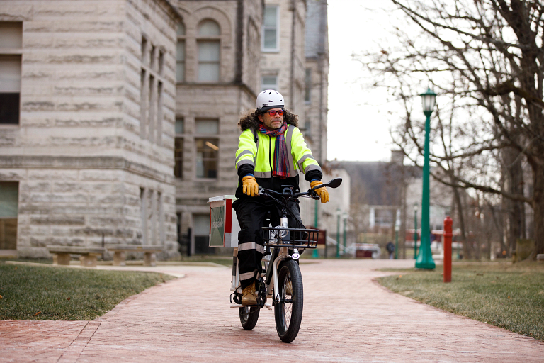 Greg Eisman riding an e-bike through campus