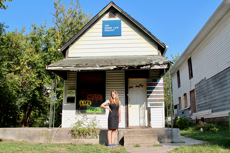 Laura Holzman stands in front of a house.