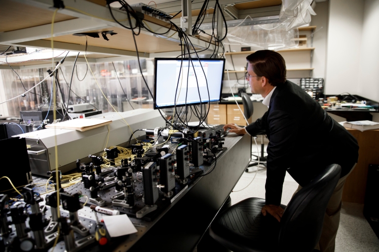 Indiana University professor Phil Richerme works with laser equipment in a lab.