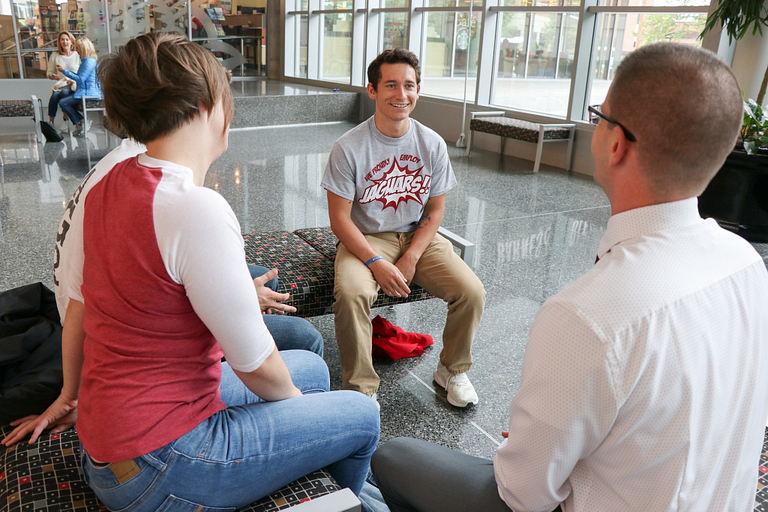 Ryan McGlinchey sits in the IUPUI campus center with his peers and advisor, smiling and talking.