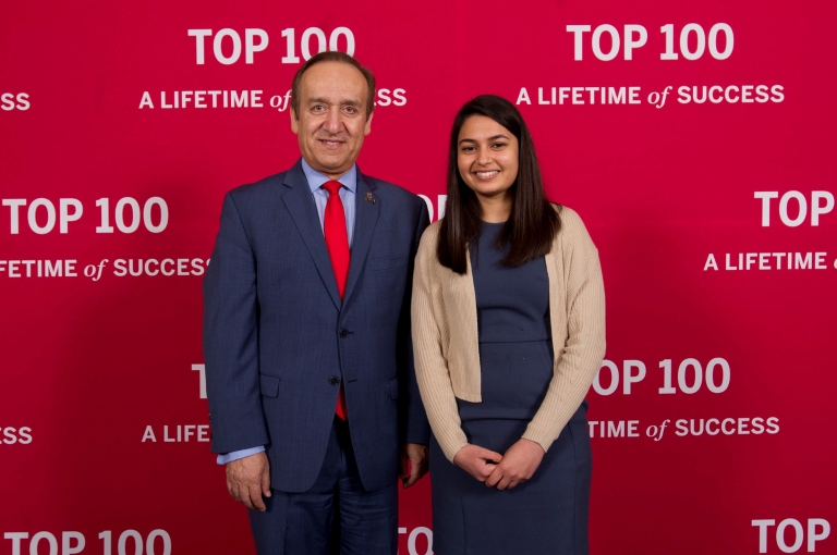 Chancellor Nasser H. Paydar stands with student Priya Dave in front of a red background.