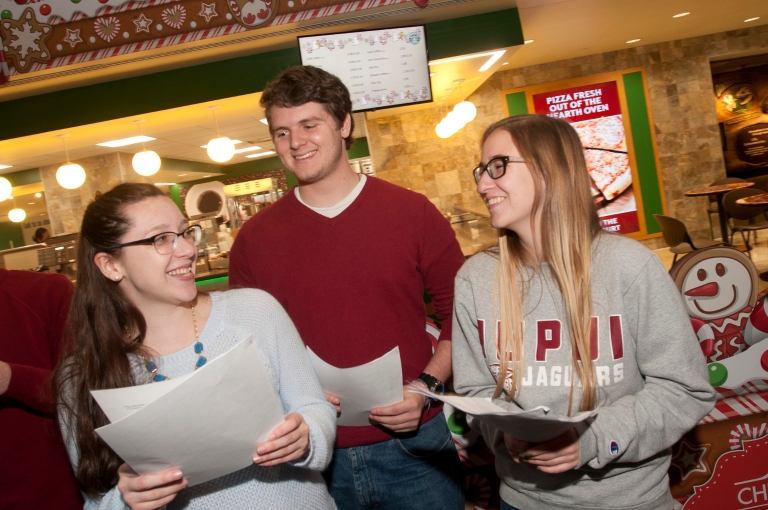 Two women and a man hold papers and smile in the Children's Museum of Indianapolis