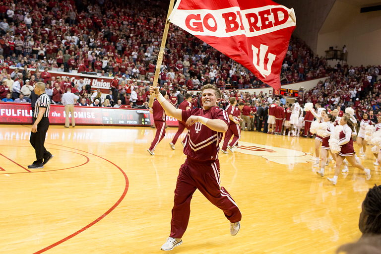 A cheerleader holds a flag that says 'go big red'