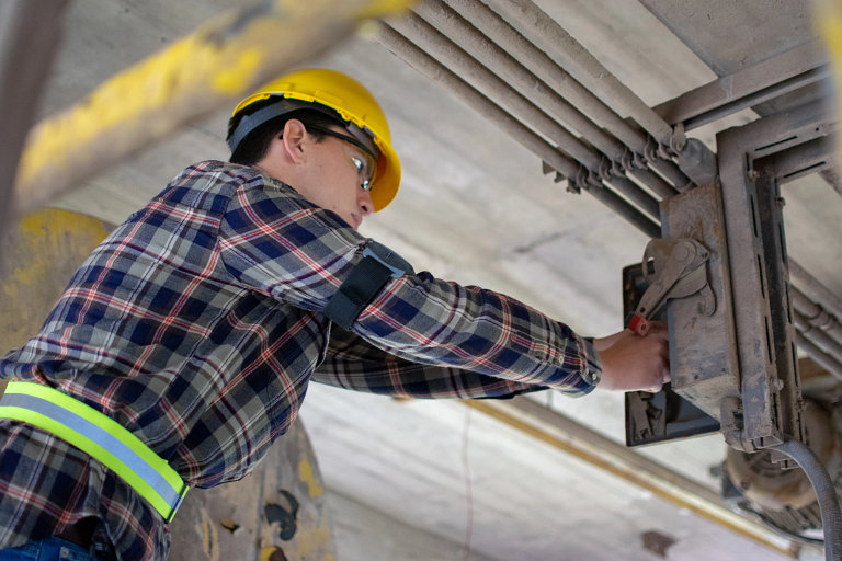 A worker wearing a safety sensor on his arm