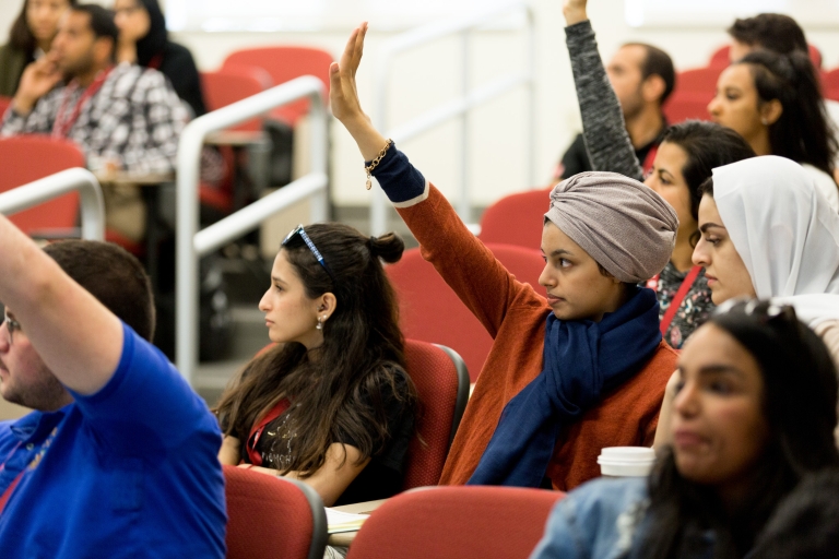 Students raise their hands to participate in a class