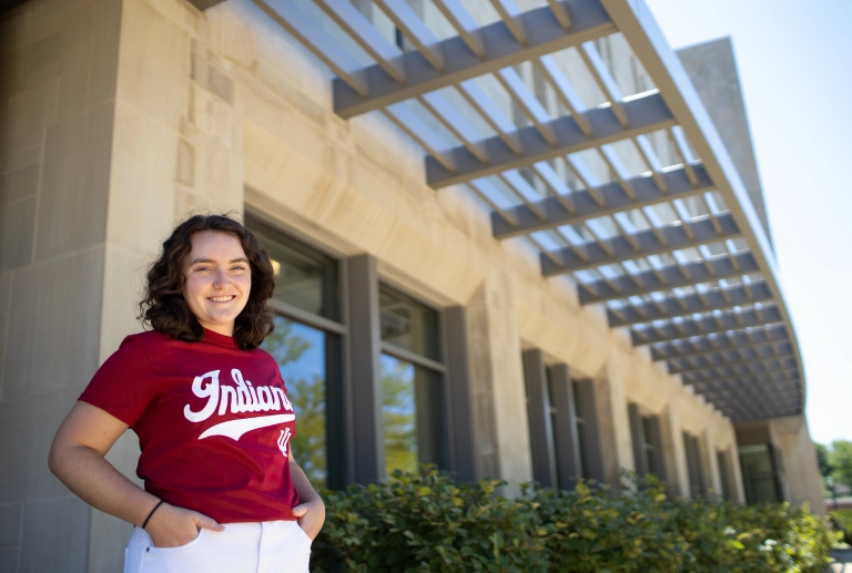 A woman wearing an Indiana University shirt stands outside a campus building
