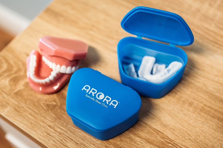 A mouthpiece, storage containers and a set of teeth on a table