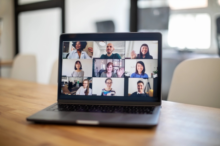 laptop screen shows people holding a virtual meeting