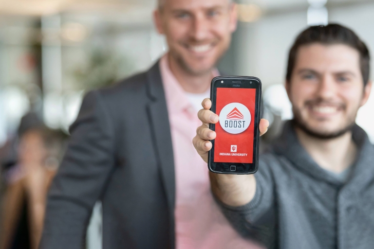 A man holding a cellphone with the Boost app on the screen