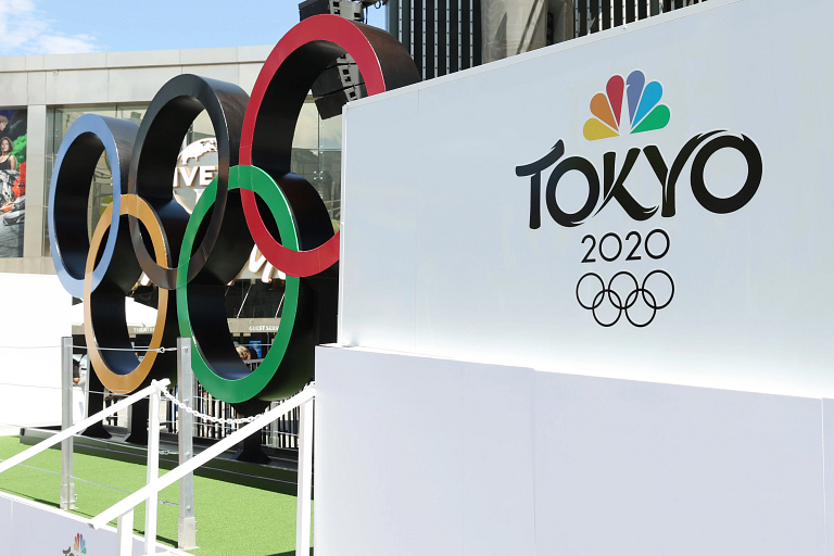 A large-scale Olympics rings statue alongside signage for NBC and Olympics