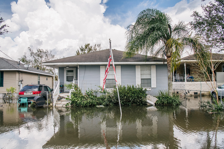 Floodwaters surround houses and a car