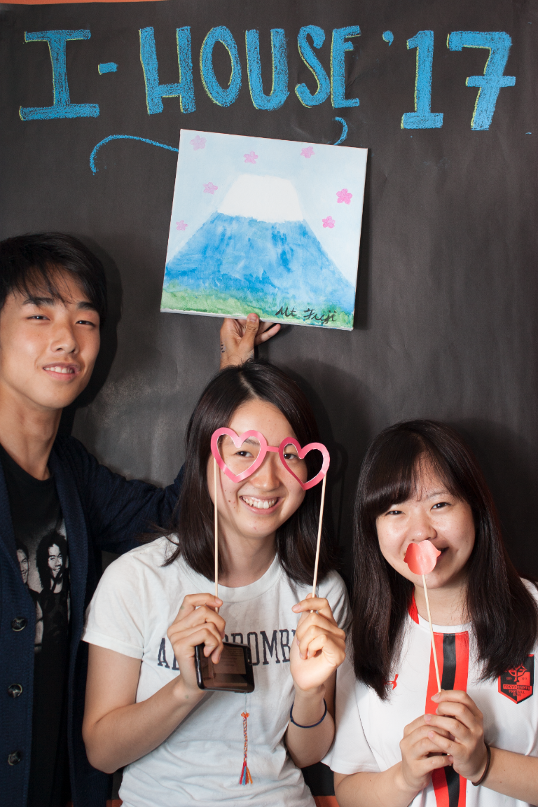 Three students pose with funny props. 
