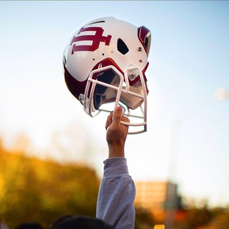 A hand holds up a football helmet