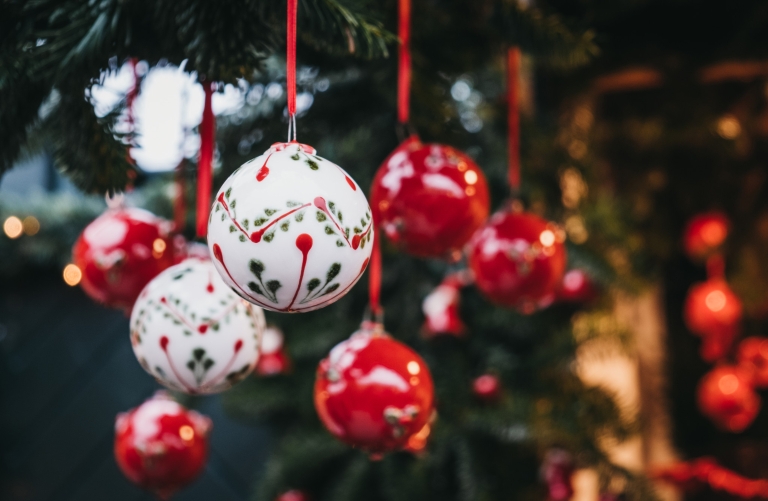 Hand-crafted red and white ornaments hang from a tree.