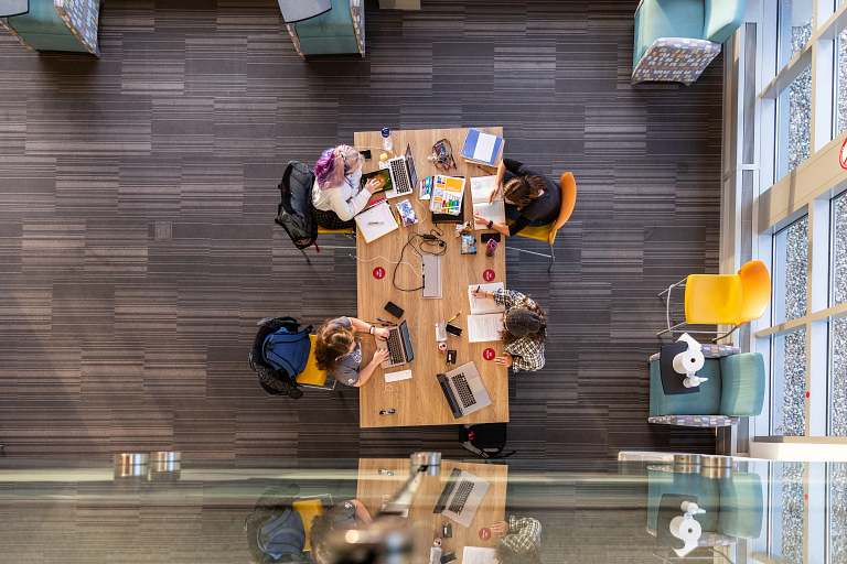 students study at a table while observing physical distancing guidelines