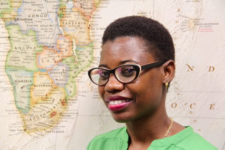 Eve Kazungu poses in front of a map of Africa