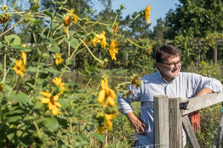 Lino Mioni leans on a fence at Hilltop Garden