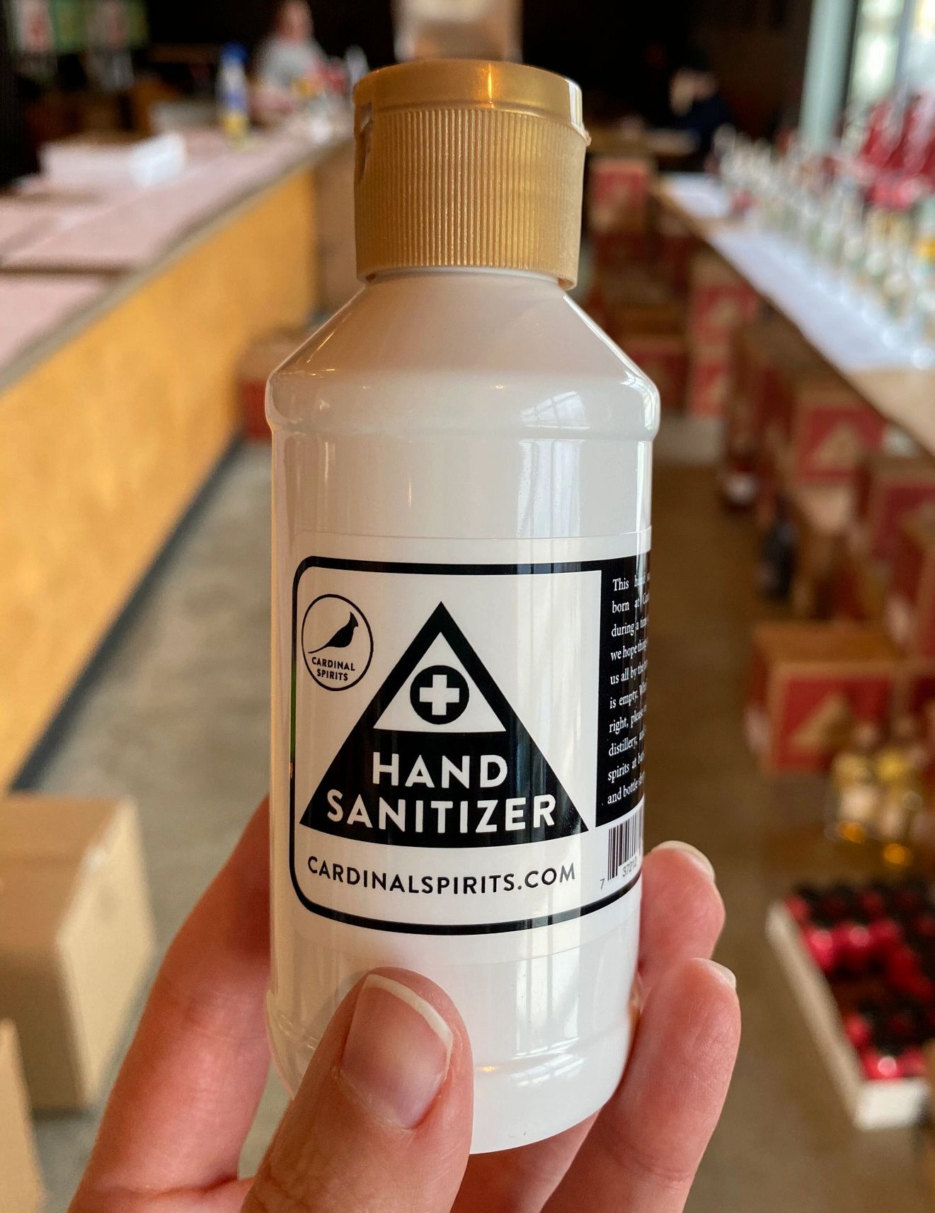 A small bottle of hand sanitizer is held by hand.