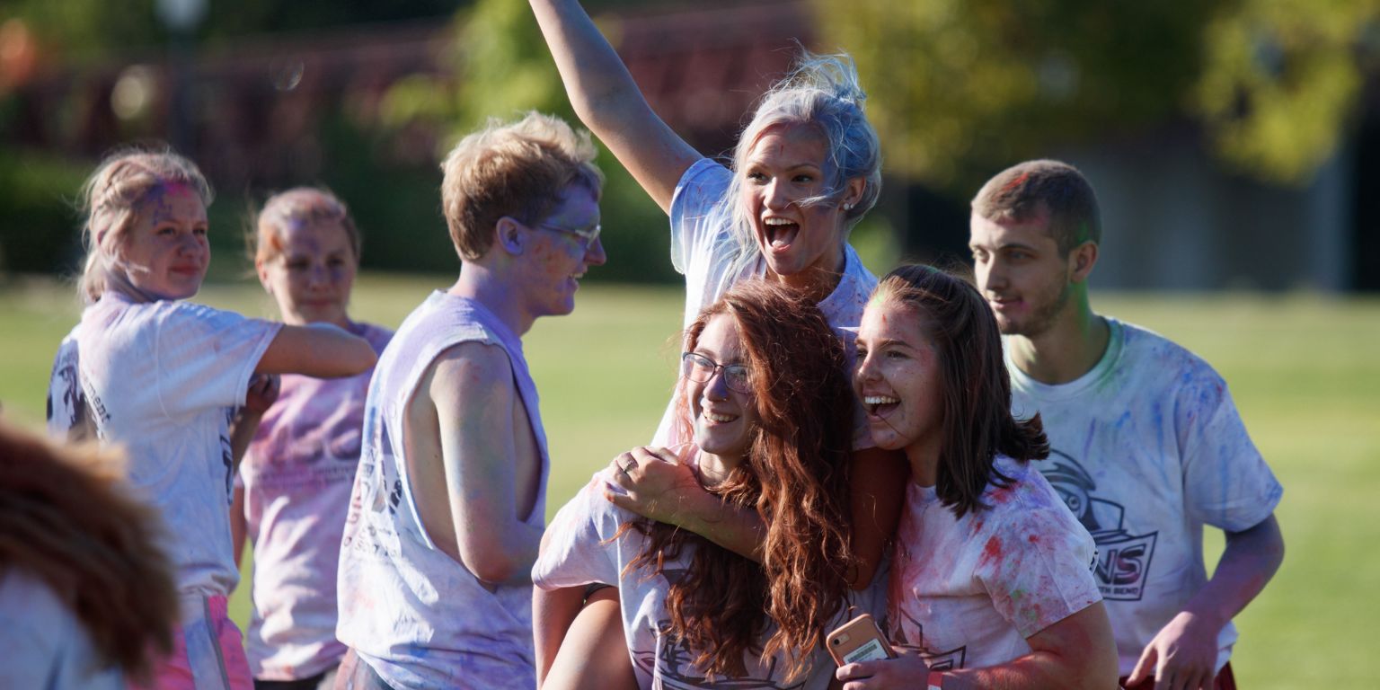 Students are covered in colored die after a run. 